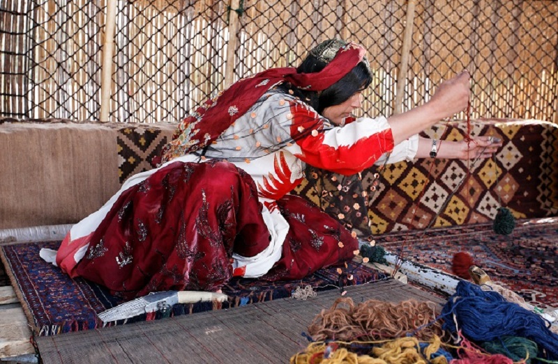 یک زن قشقایی در حال بافت قالی در استان فارس با مهارت های سنتی این هنر