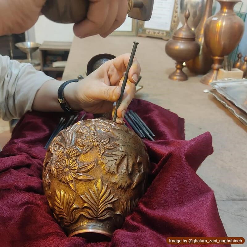 An artist practicing toreutics on a metal vase